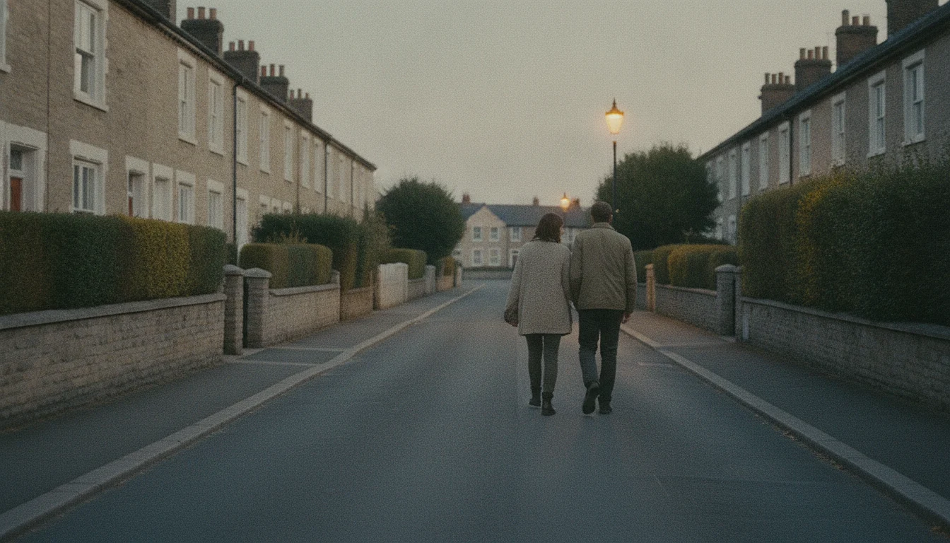 Two people walking home very close together along an evening street, seen from behind.